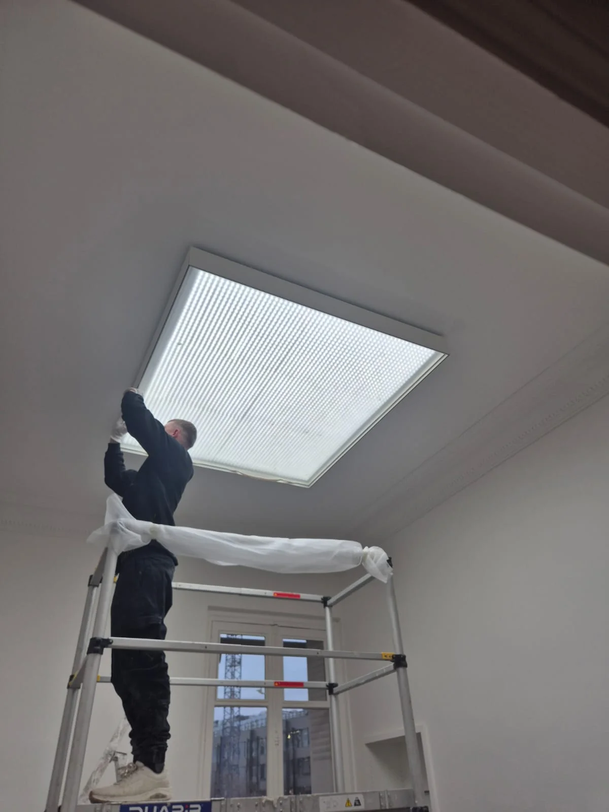 Installer fitting the translucent stretch fabric diffuser